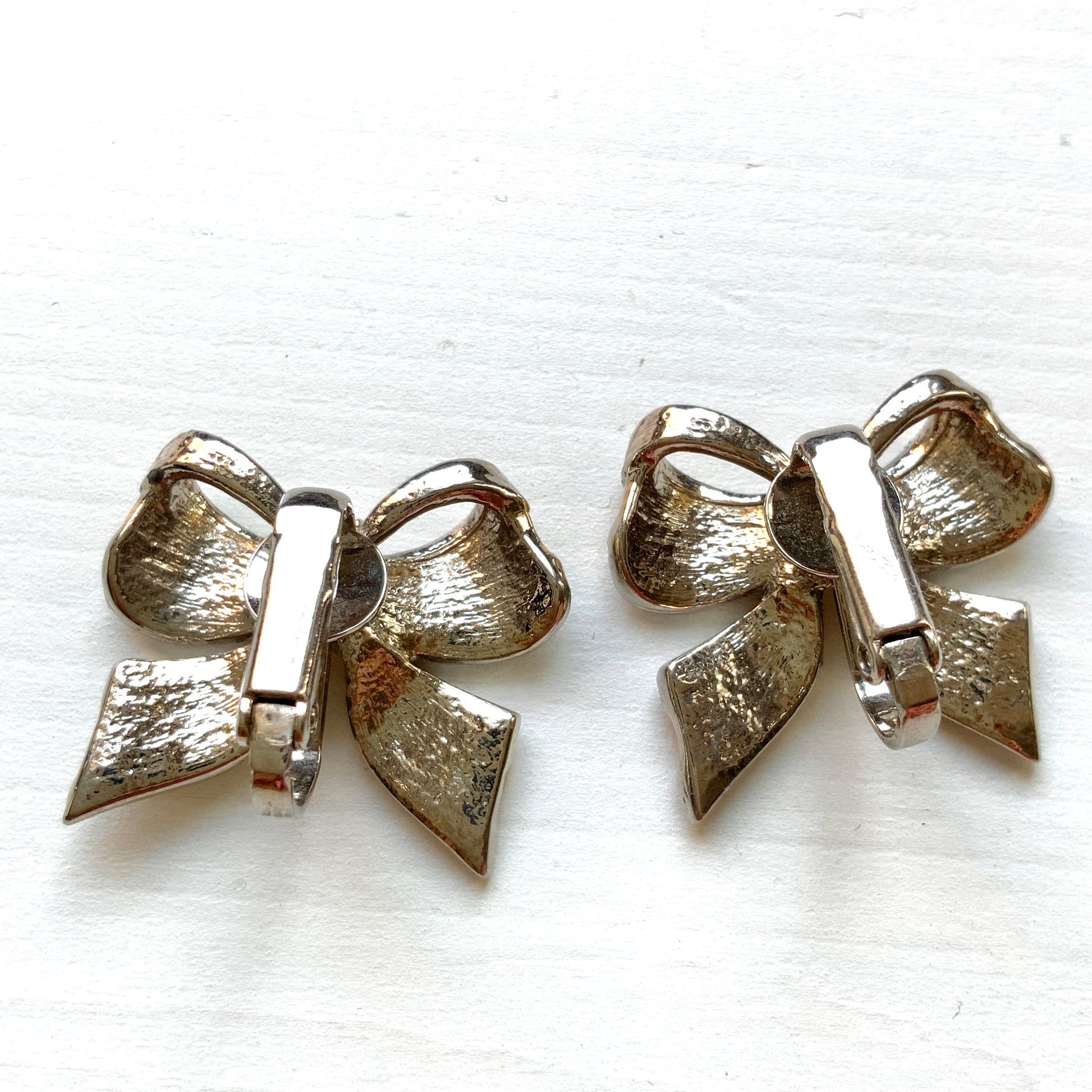 Vintage clip-on earrings in a bow design featuring both gold-tone and silver-tone metal. ゴールドトーンとシルバートーンのリボンのクリップイヤリング。 