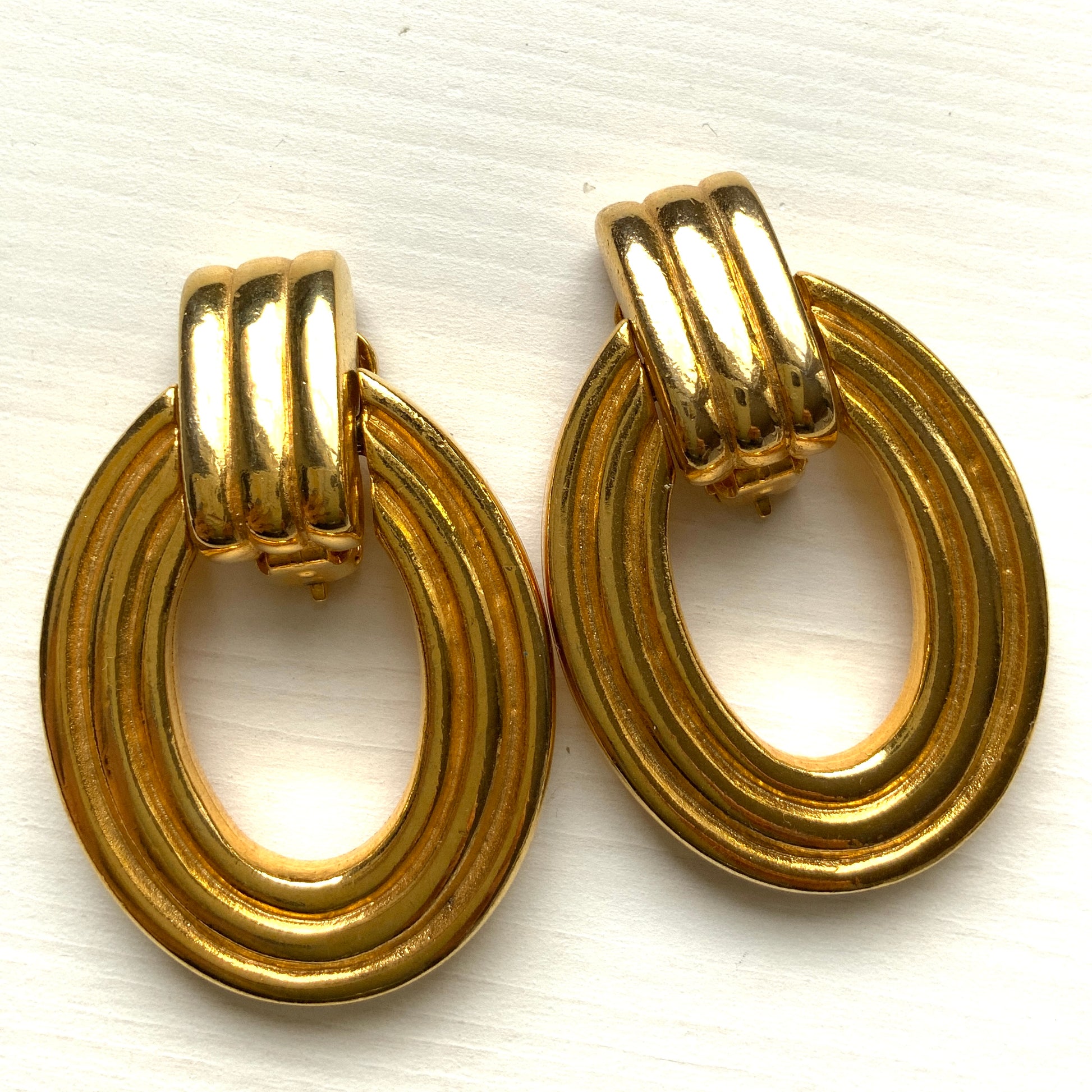 Gold-tone door knocker earrings with subtle linear detailing. ラインが入ったゴールドトーンのドアノッカーイヤリング。 