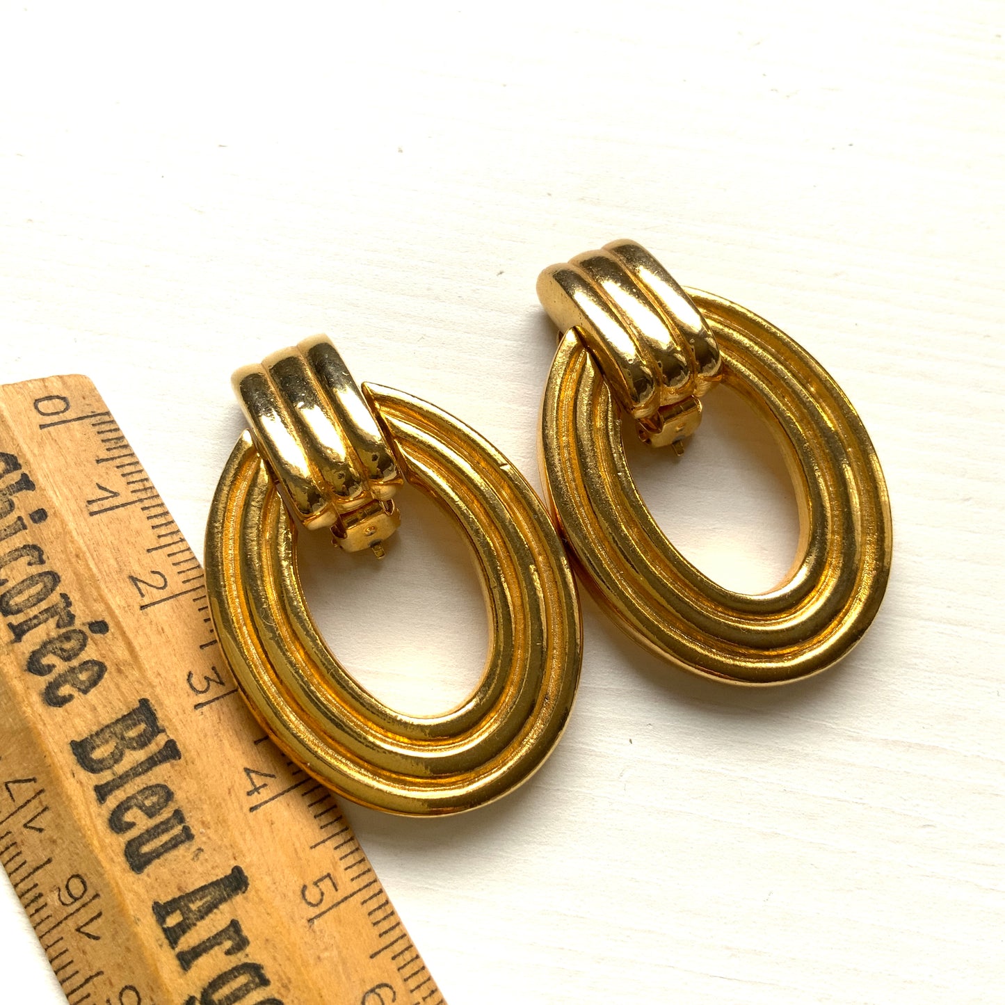 Gold-tone door knocker earrings with subtle linear detailing. ラインが入ったゴールドトーンのドアノッカーイヤリング。 