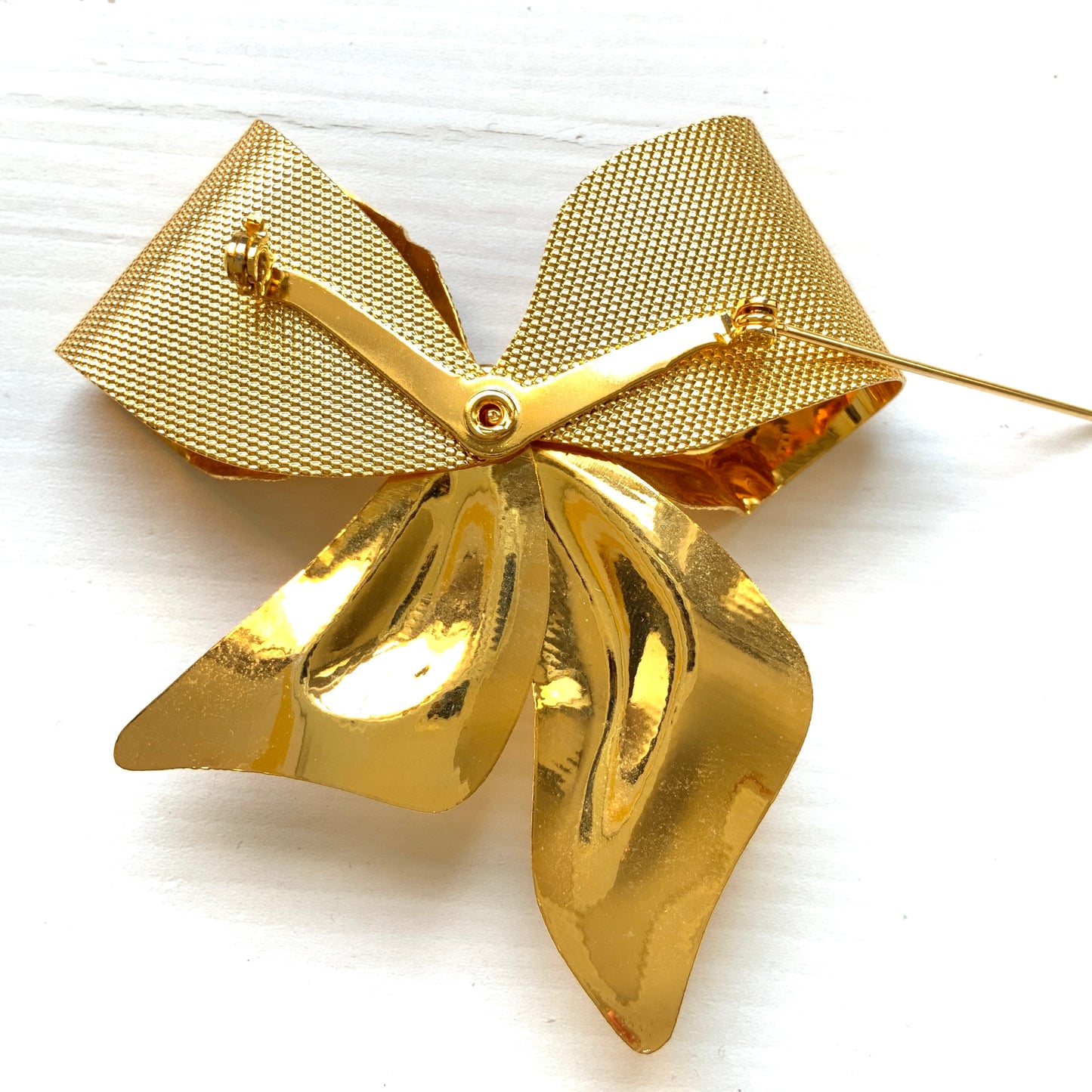 Vintage brooch in the shape of a large gold-tone bow. 大きなゴールドトーンメタルのリボンのブローチ。