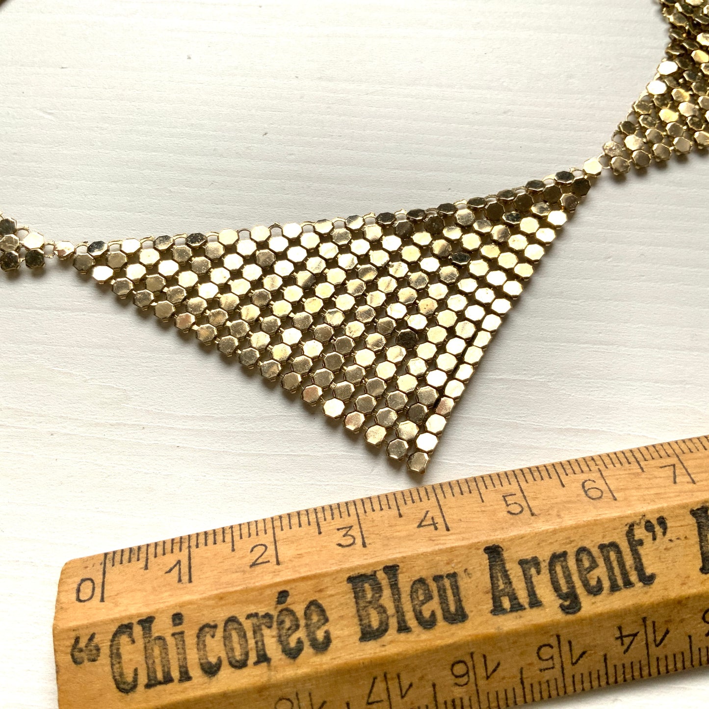 Gold-tone necklace featuring a combination of triangular metal mesh panels. 三角形のメタルメッシュを組み合わせた、ゴールドトーンのネックレス。