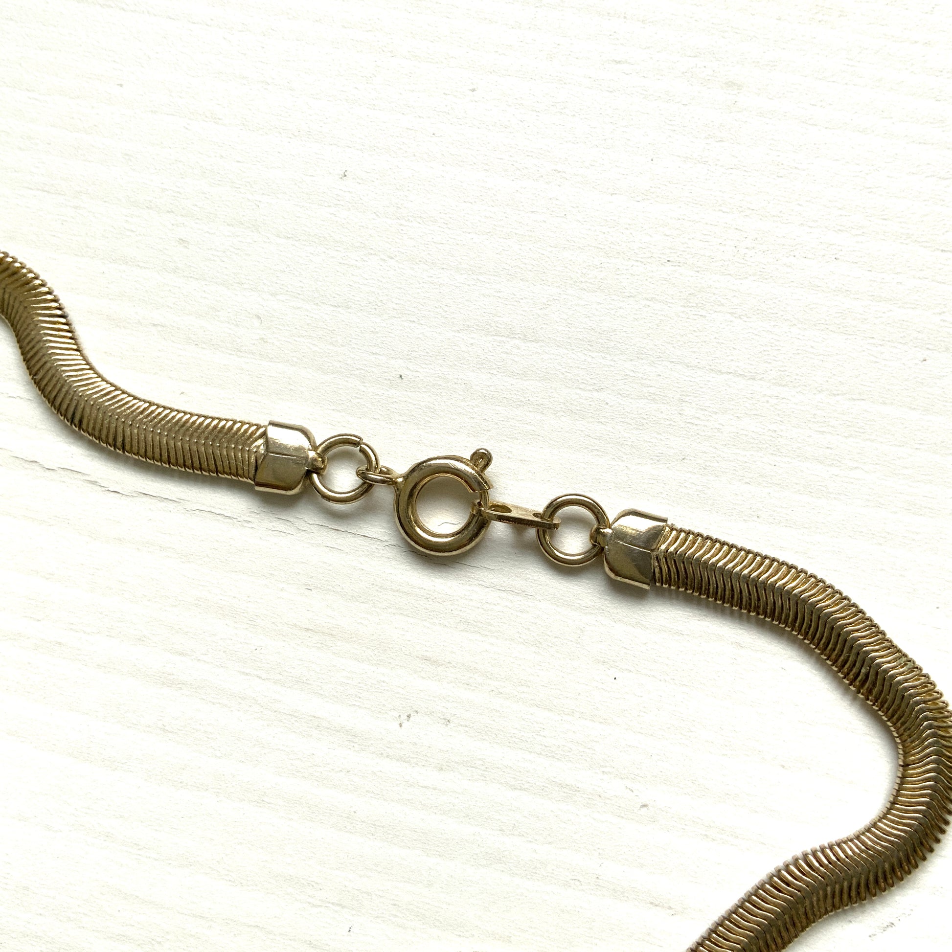 Gold-tone necklace featuring a combination of triangular metal mesh panels. 三角形のメタルメッシュを組み合わせた、ゴールドトーンのネックレス。