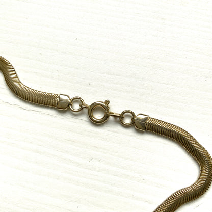 Gold-tone necklace featuring a combination of triangular metal mesh panels. 三角形のメタルメッシュを組み合わせた、ゴールドトーンのネックレス。