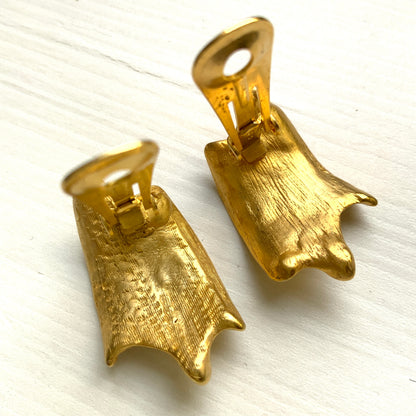 Matte gold-tone clip-on earrings with a simple abstract form. シンプルな抽象的フォルムが印象的な、マットゴールドトーンのクリップイヤリング。