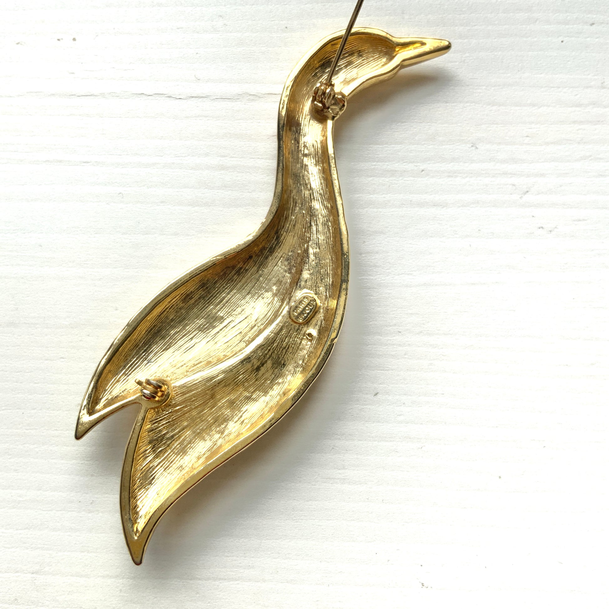 A graceful bird brooch defined by its smooth, flowing lines.  なめらかな曲線で描かれたフォルムが優雅な、鳥のブローチ。