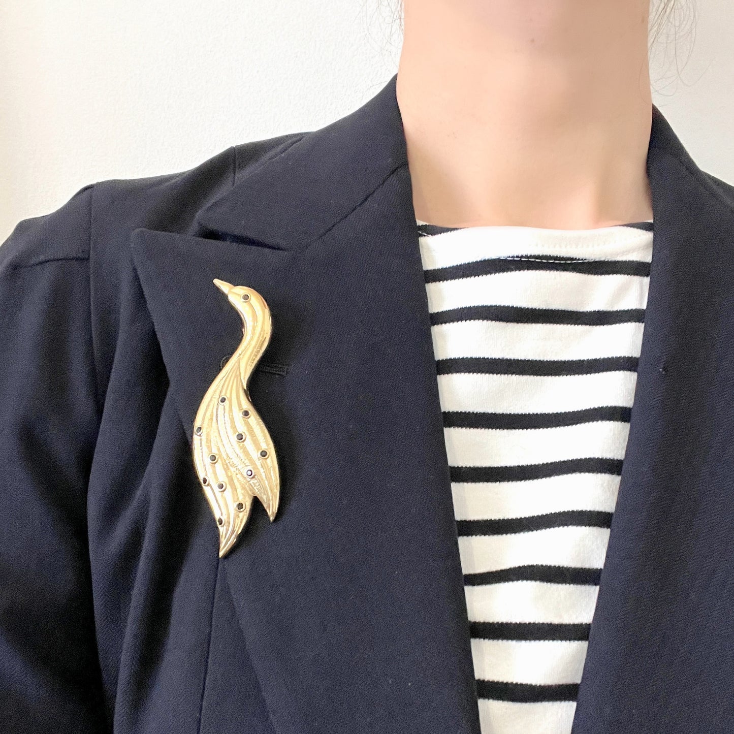 A graceful bird brooch defined by its smooth, flowing lines.  なめらかな曲線で描かれたフォルムが優雅な、鳥のブローチ。