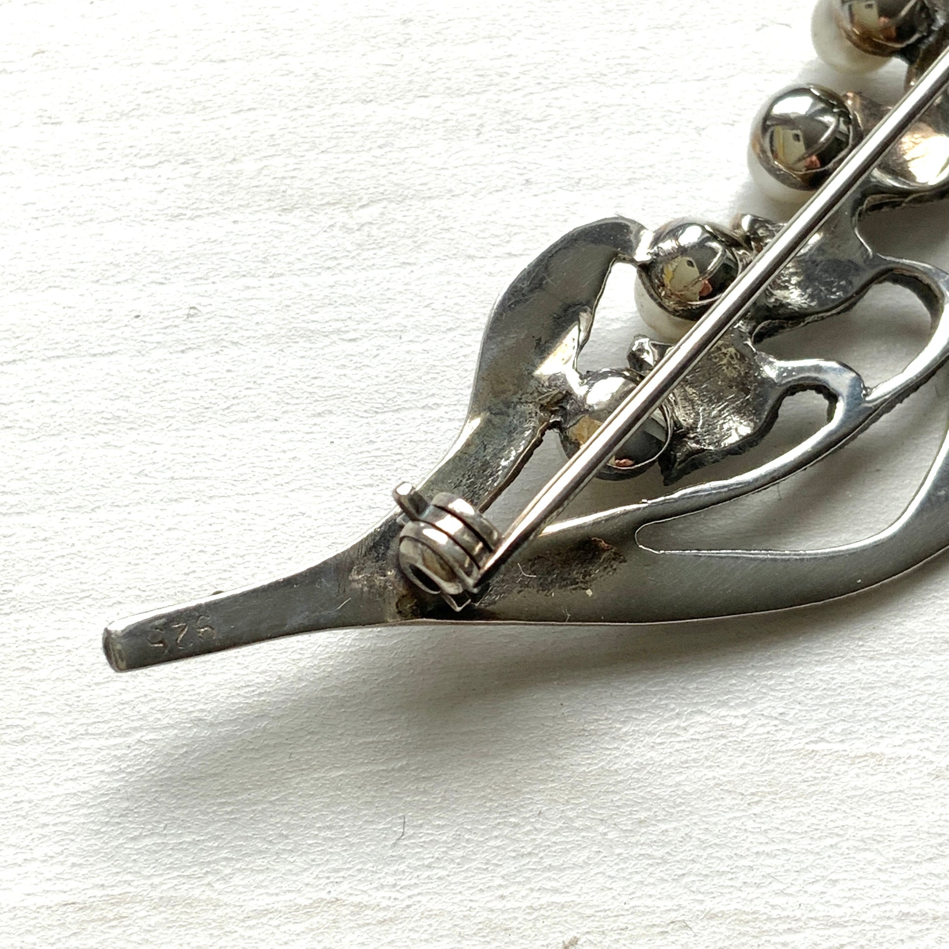 A silver brooch featuring lily of the valley set with pearls. パールがあしらわれたスズランモチーフのシルバーブローチ。