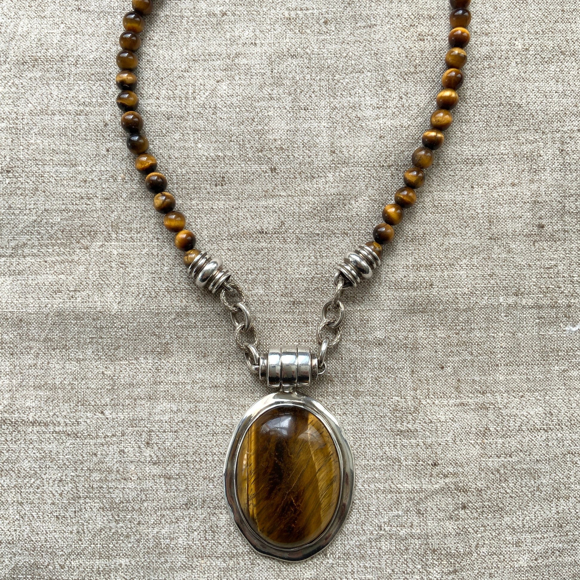 A bold oval-shaped tiger's eye stone takes centre stage in this striking silver necklace by Joseph Esposito. 大ぶりのオーバル型タイガーアイが印象的な、ジョセフ・エスポジートによるシルバーネックレス。
