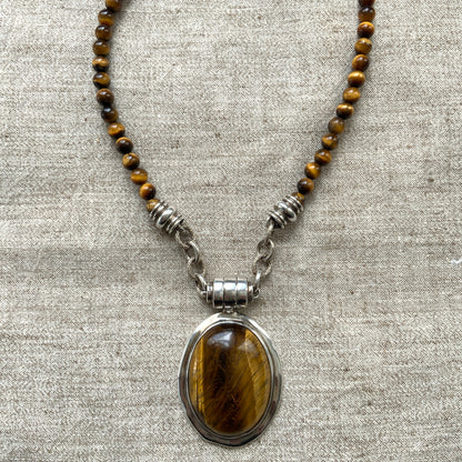 A bold oval-shaped tiger's eye stone takes centre stage in this striking silver necklace by Joseph Esposito. 大ぶりのオーバル型タイガーアイが印象的な、ジョセフ・エスポジートによるシルバーネックレス。
