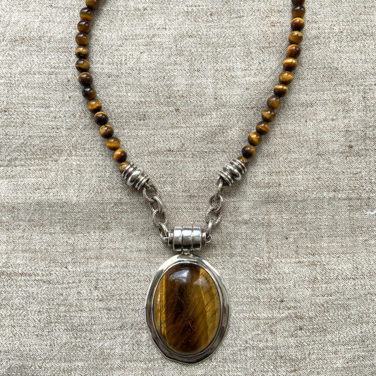 A bold oval-shaped tiger's eye stone takes centre stage in this striking silver necklace by Joseph Esposito. 大ぶりのオーバル型タイガーアイが印象的な、ジョセフ・エスポジートによるシルバーネックレス。