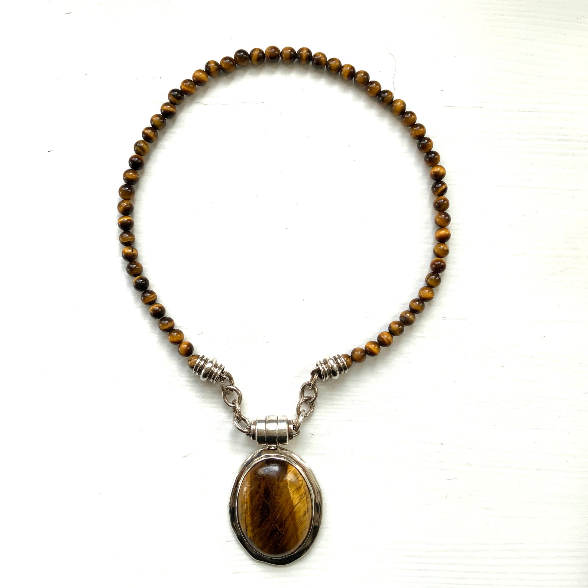 A bold oval-shaped tiger's eye stone takes centre stage in this striking silver necklace by Joseph Esposito. 大ぶりのオーバル型タイガーアイが印象的な、ジョセフ・エスポジートによるシルバーネックレス。