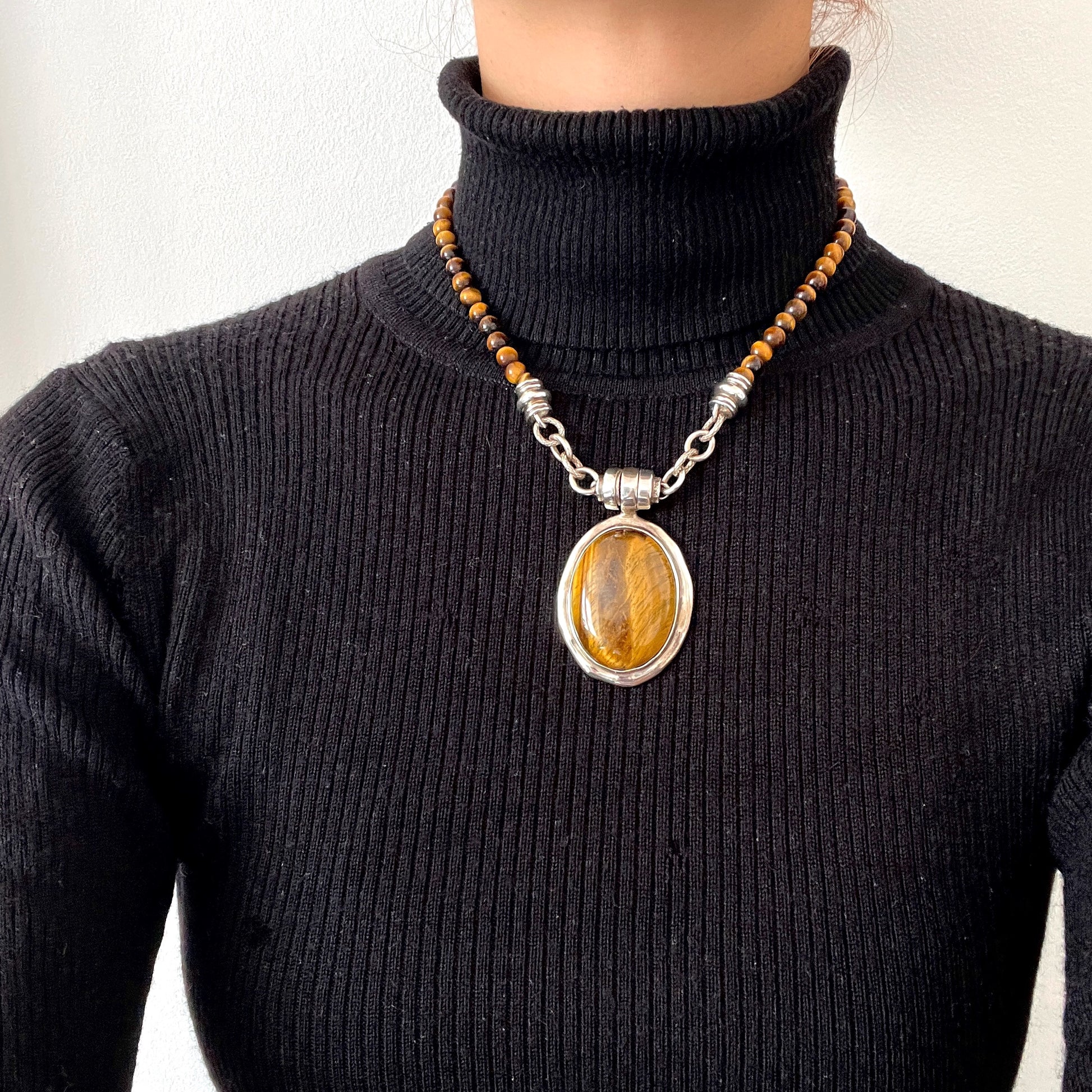 A bold oval-shaped tiger's eye stone takes centre stage in this striking silver necklace by Joseph Esposito. 大ぶりのオーバル型タイガーアイが印象的な、ジョセフ・エスポジートによるシルバーネックレス。