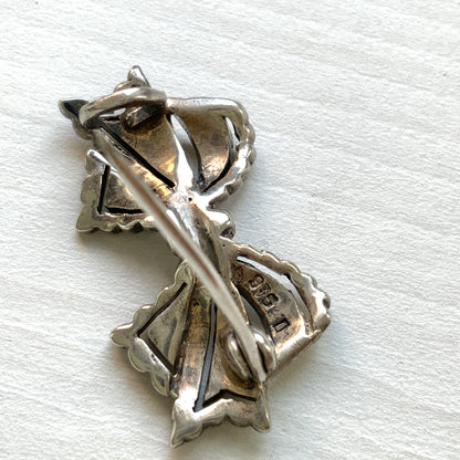 A small bow brooch set with marcasites in silver. シルバーにマーカサイトがあしらわれた小さなリボンのブローチ。 