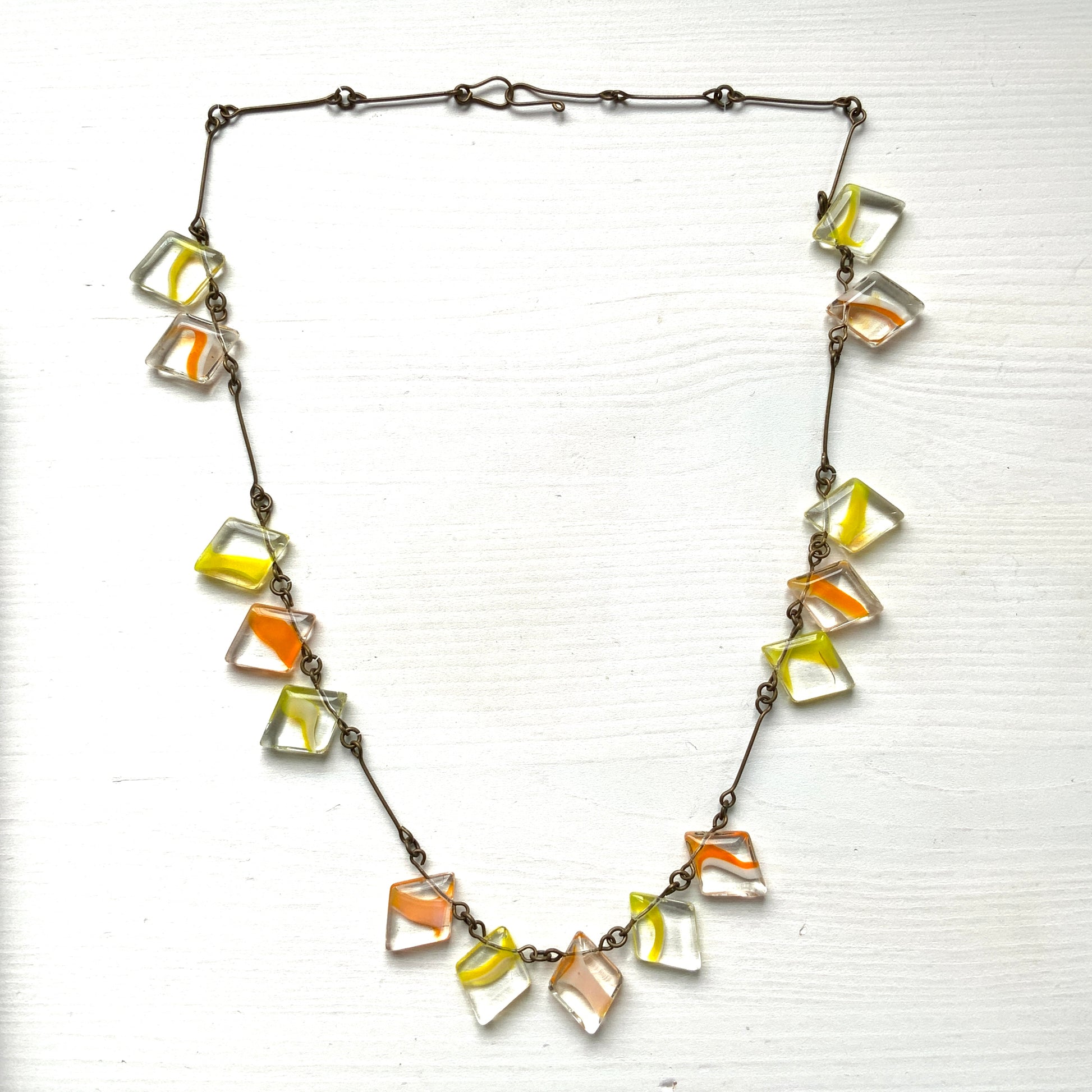 Necklace featuring diamond-shaped clear glass beads infused with shades of yellow, orange, and white. クリアのダイヤ型グラスにイエロー、オレンジ、ホワイトのカラーが入ったビーズを使ったネックレス。 