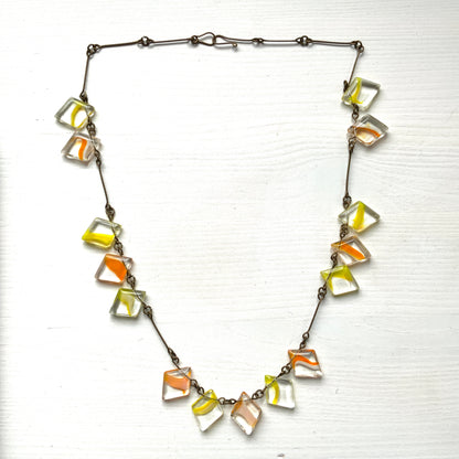 Necklace featuring diamond-shaped clear glass beads infused with shades of yellow, orange, and white. クリアのダイヤ型グラスにイエロー、オレンジ、ホワイトのカラーが入ったビーズを使ったネックレス。 