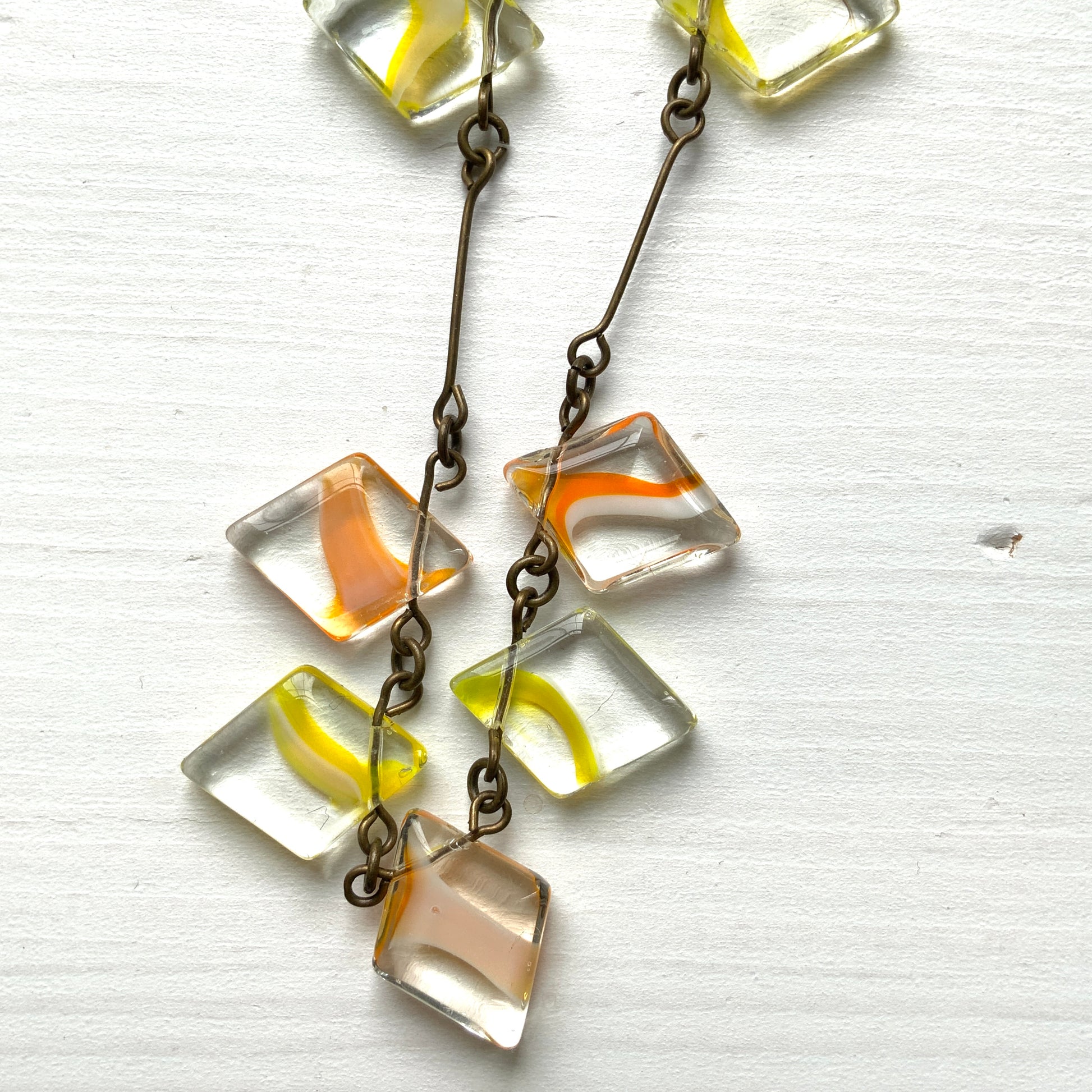 Necklace featuring diamond-shaped clear glass beads infused with shades of yellow, orange, and white. クリアのダイヤ型グラスにイエロー、オレンジ、ホワイトのカラーが入ったビーズを使ったネックレス。 