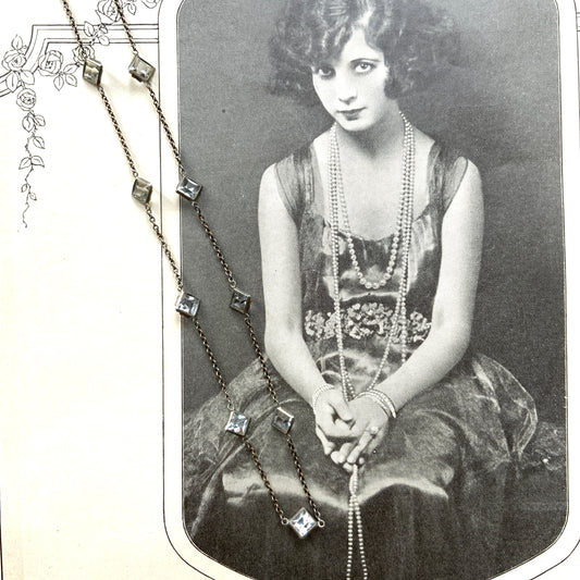 Platinon necklace set with diamond-shaped clear glass stones placed at intervals along the chain. ダイヤ型のクリアグラスがとびとびについたプラチノンのネックレス。