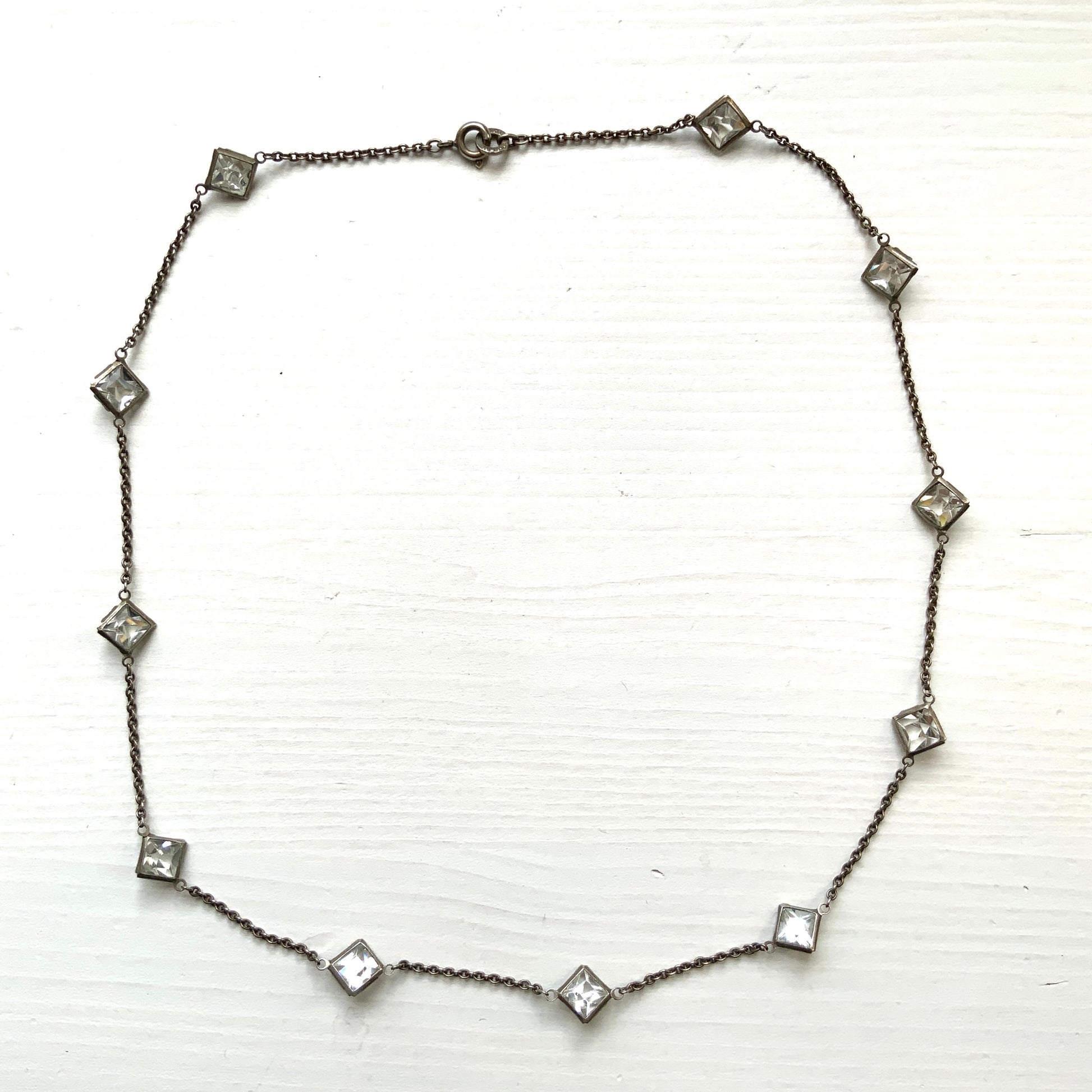 Platinon necklace set with diamond-shaped clear glass stones placed at intervals along the chain. ダイヤ型のクリアグラスがとびとびについたプラチノンのネックレス。