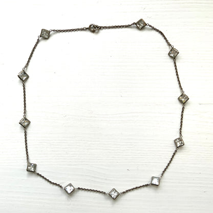Platinon necklace set with diamond-shaped clear glass stones placed at intervals along the chain. ダイヤ型のクリアグラスがとびとびについたプラチノンのネックレス。