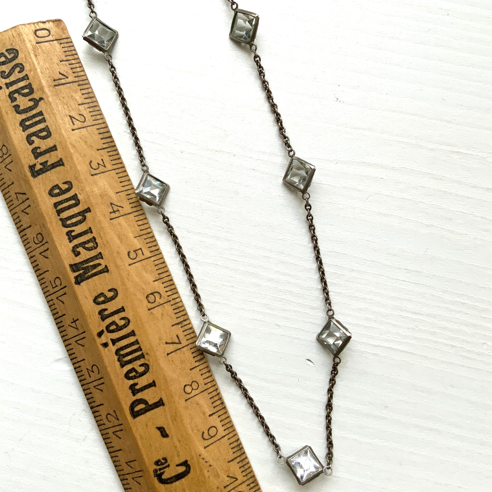 Platinon necklace set with diamond-shaped clear glass stones placed at intervals along the chain. ダイヤ型のクリアグラスがとびとびについたプラチノンのネックレス。