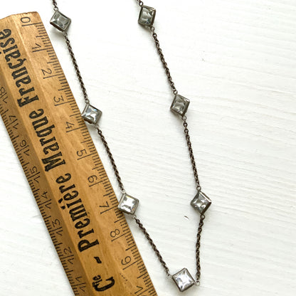 Platinon necklace set with diamond-shaped clear glass stones placed at intervals along the chain. ダイヤ型のクリアグラスがとびとびについたプラチノンのネックレス。