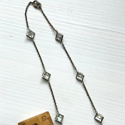 Platinon necklace set with diamond-shaped clear glass stones placed at intervals along the chain. ダイヤ型のクリアグラスがとびとびについたプラチノンのネックレス。