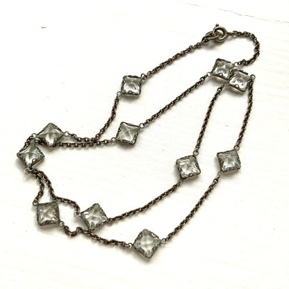 Platinon necklace set with diamond-shaped clear glass stones placed at intervals along the chain. ダイヤ型のクリアグラスがとびとびについたプラチノンのネックレス。