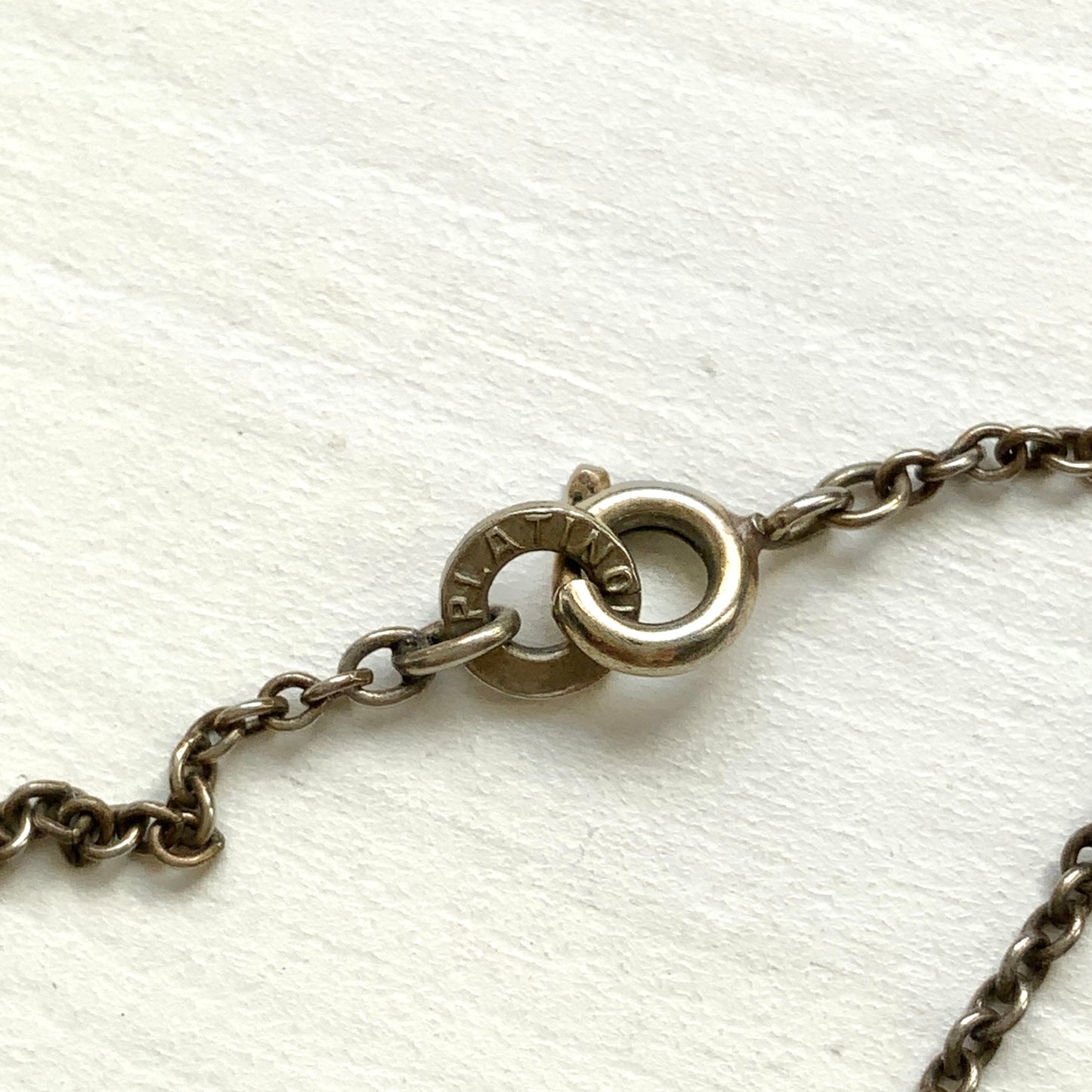Platinon necklace set with diamond-shaped clear glass stones placed at intervals along the chain. ダイヤ型のクリアグラスがとびとびについたプラチノンのネックレス。