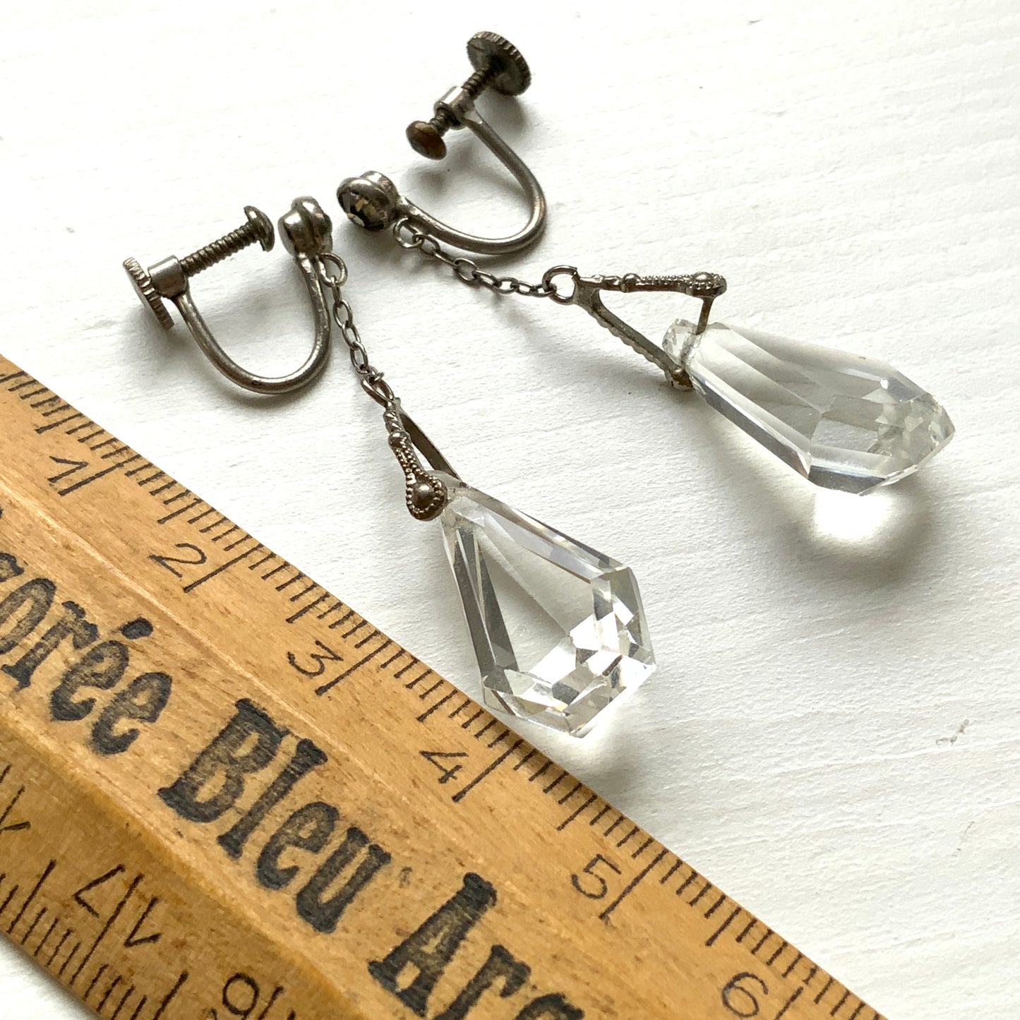 Screw-back earrings featuring clear faceted glass in a unique triangular form. ユニークな三角フォルムのファセットグラスが揺れる、スクリューイヤリング。