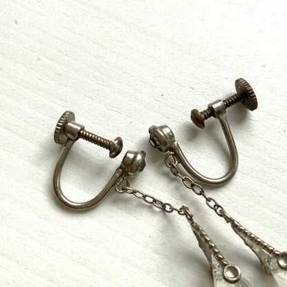 Screw-back earrings featuring clear faceted glass in a unique triangular form. ユニークな三角フォルムのファセットグラスが揺れる、スクリューイヤリング。