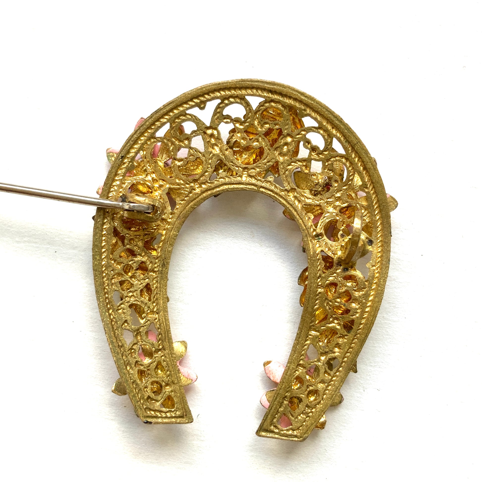 A horseshoe motif brooch adorned with pink enamel flowers. ピンクのエナメルのお花が飾られた、馬蹄モチーフのブローチ。 