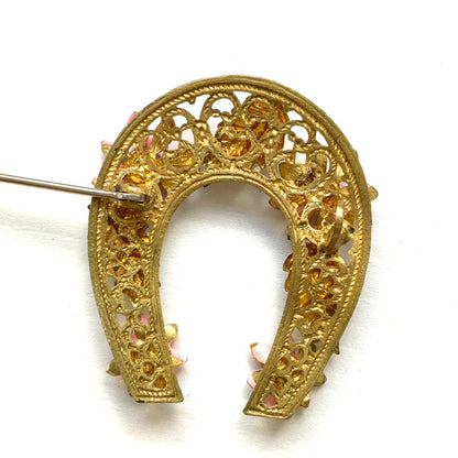 A horseshoe motif brooch adorned with pink enamel flowers. ピンクのエナメルのお花が飾られた、馬蹄モチーフのブローチ。 