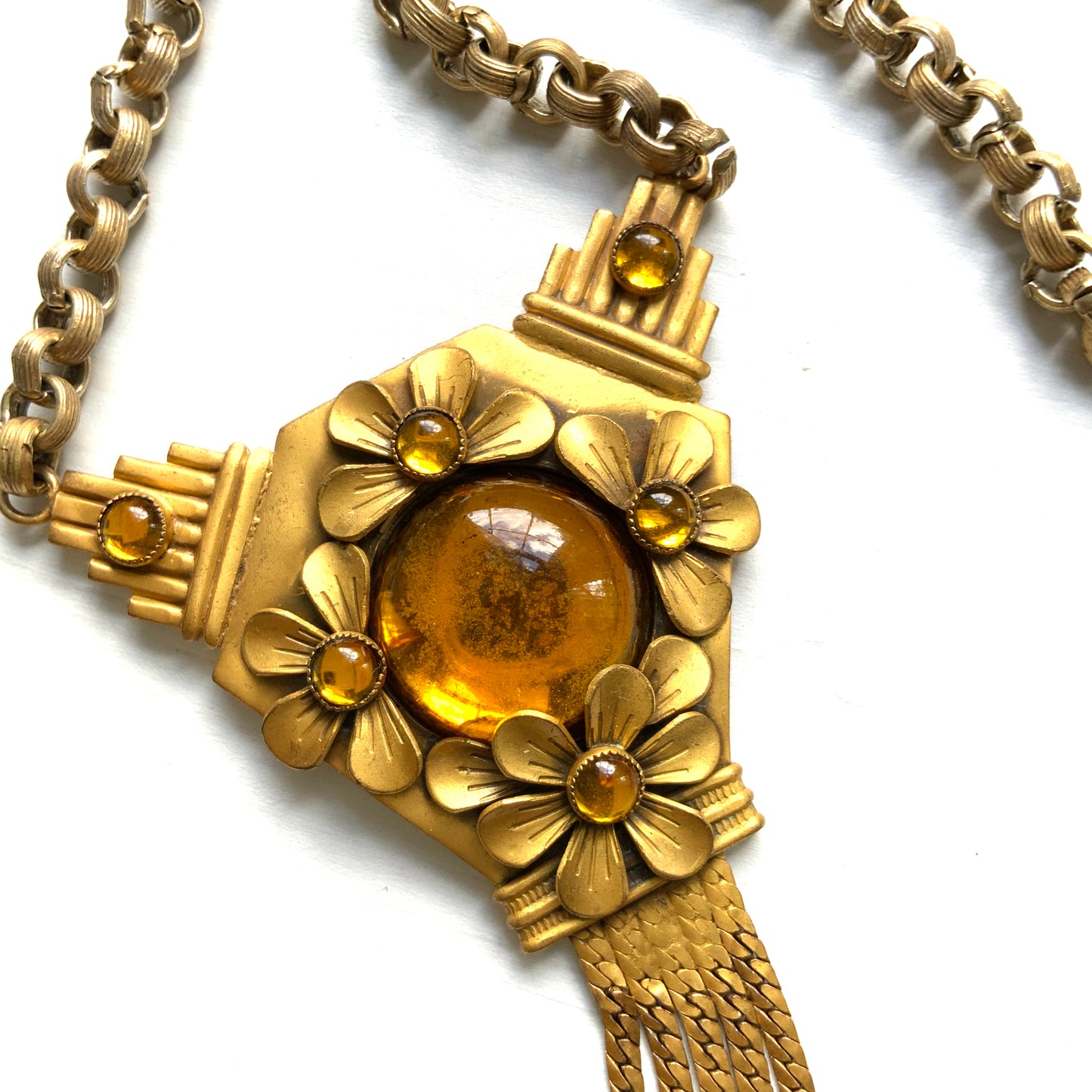A bright orange cabochon glass, like a little sun, is surrounded by gold-tone metal flowers in this stunning necklace. お日様のように明るいオレンジのカボショングラスを、ゴールドトーンメタルのお花がぐるりと囲んだネックレス。 