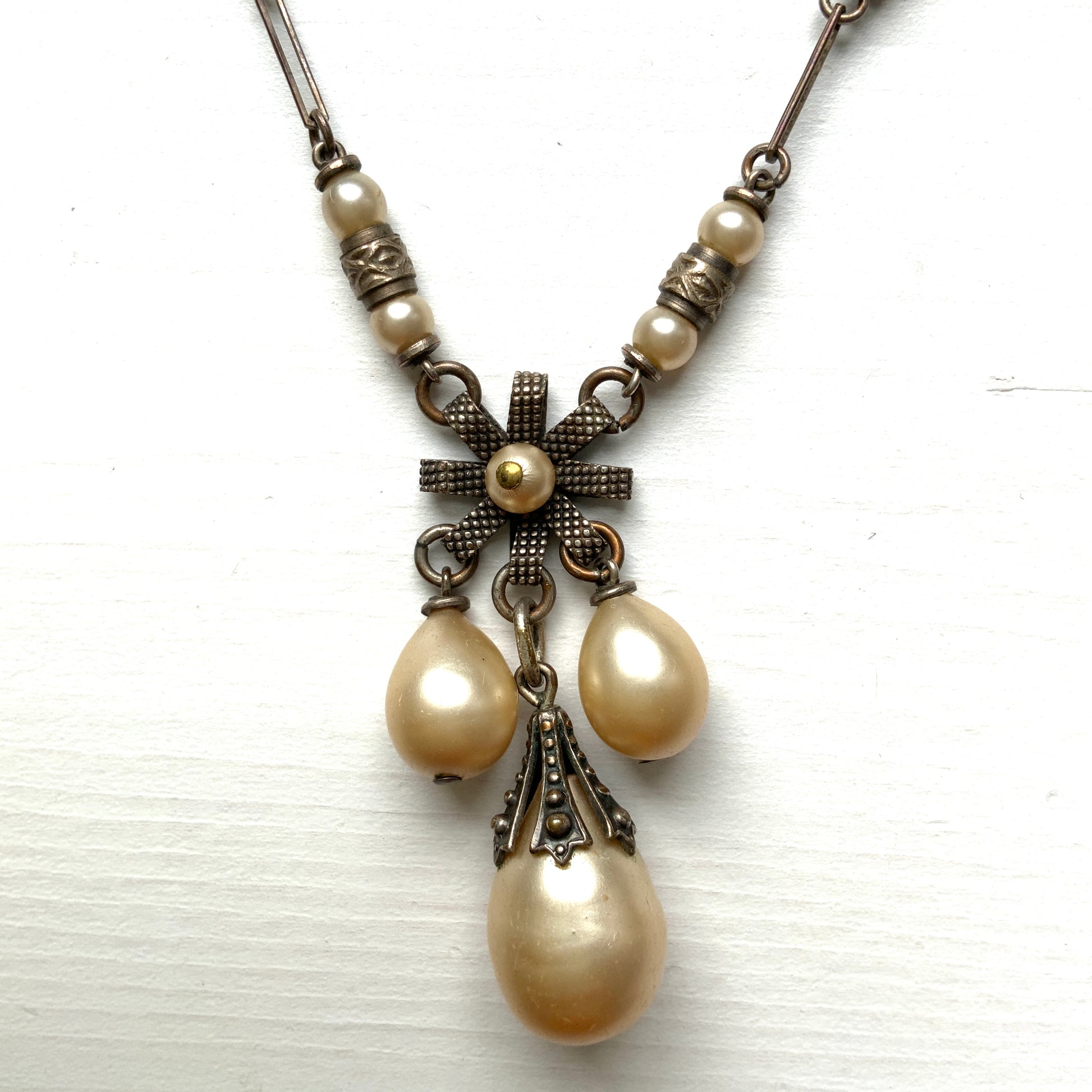 A necklace featuring metal flowers reminiscent of daisies, from which dangle chunky handmade teardrop glass pearls. デイジーのようなメタルのお花に、ゴロンとしたハンドメイドのティアドロップグラスパールがさがったネックレス。 