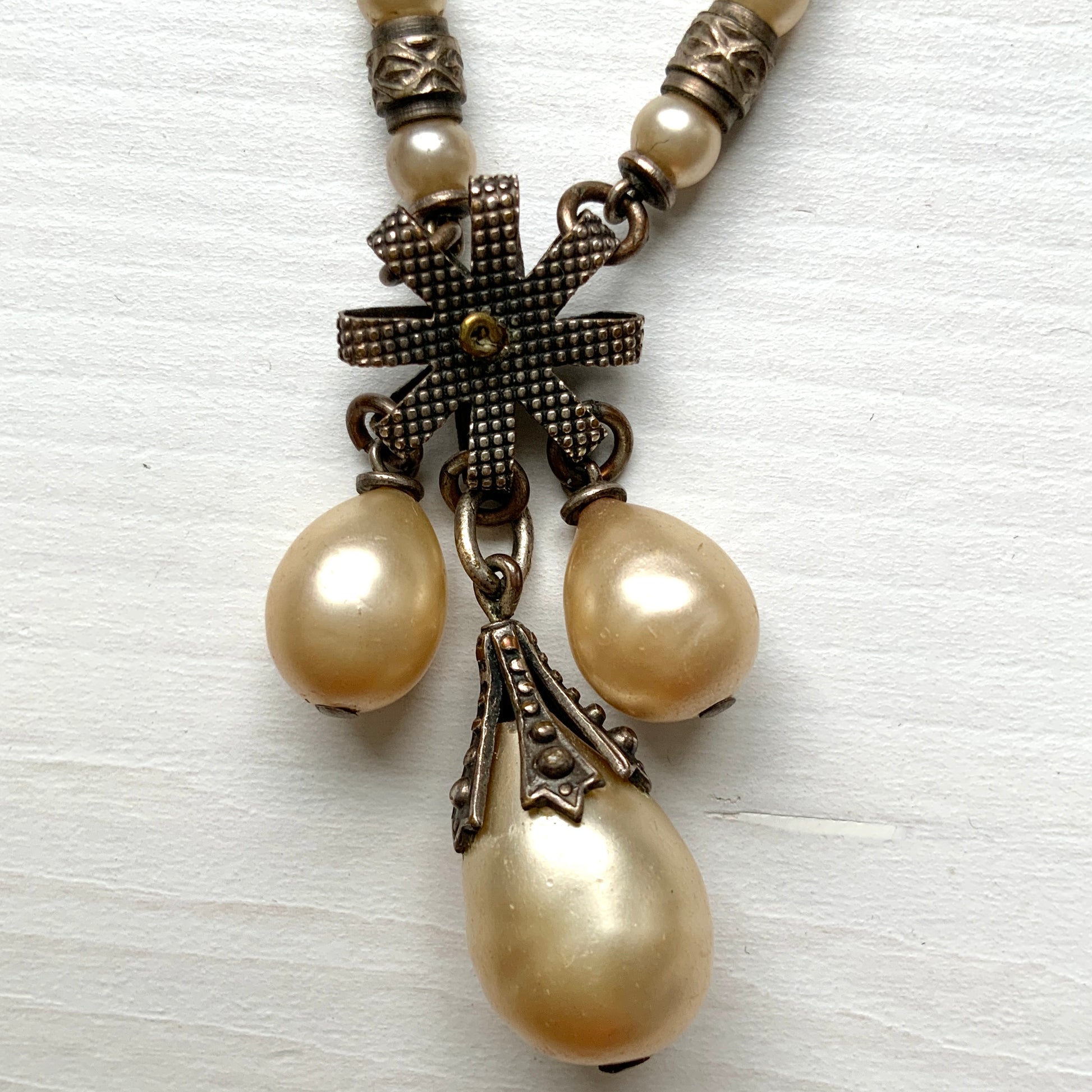 A necklace featuring metal flowers reminiscent of daisies, from which dangle chunky handmade teardrop glass pearls. デイジーのようなメタルのお花に、ゴロンとしたハンドメイドのティアドロップグラスパールがさがったネックレス。 