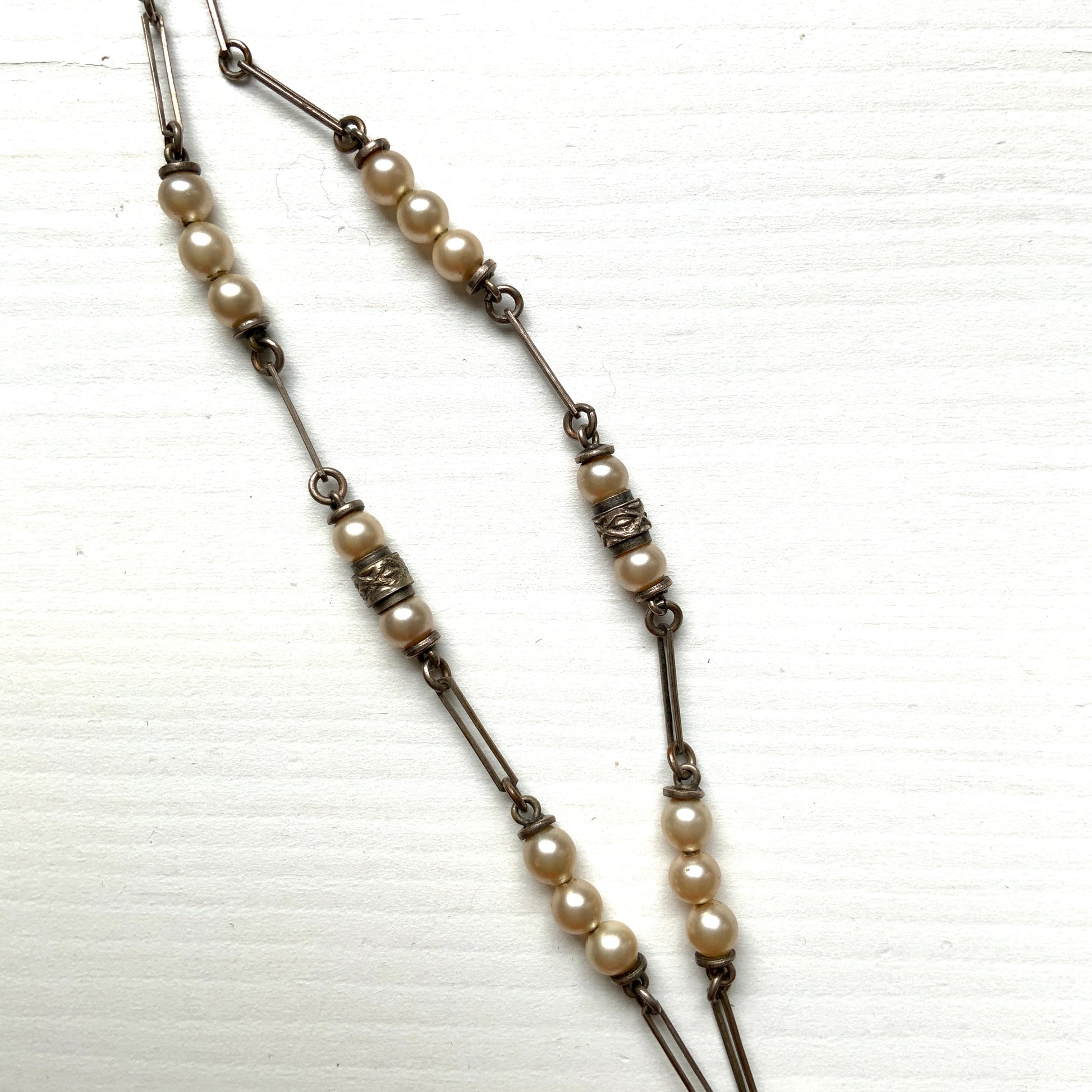 A necklace featuring metal flowers reminiscent of daisies, from which dangle chunky handmade teardrop glass pearls. デイジーのようなメタルのお花に、ゴロンとしたハンドメイドのティアドロップグラスパールがさがったネックレス。 