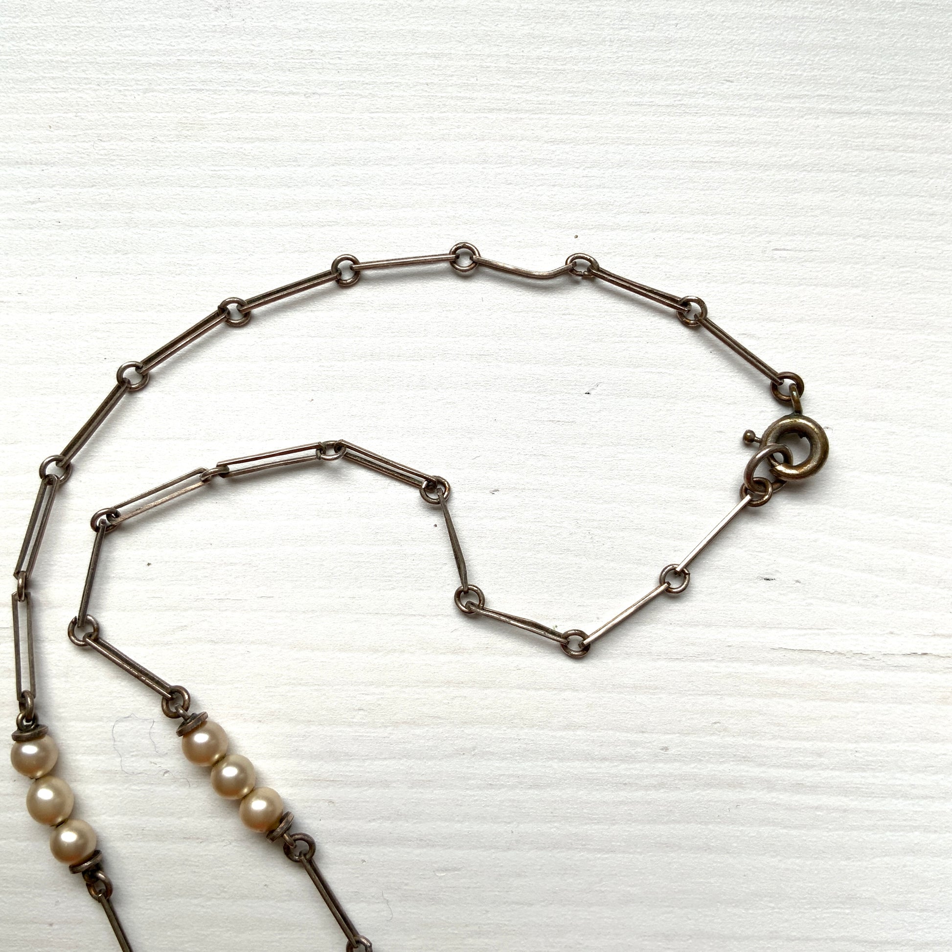 A necklace featuring metal flowers reminiscent of daisies, from which dangle chunky handmade teardrop glass pearls. デイジーのようなメタルのお花に、ゴロンとしたハンドメイドのティアドロップグラスパールがさがったネックレス。 