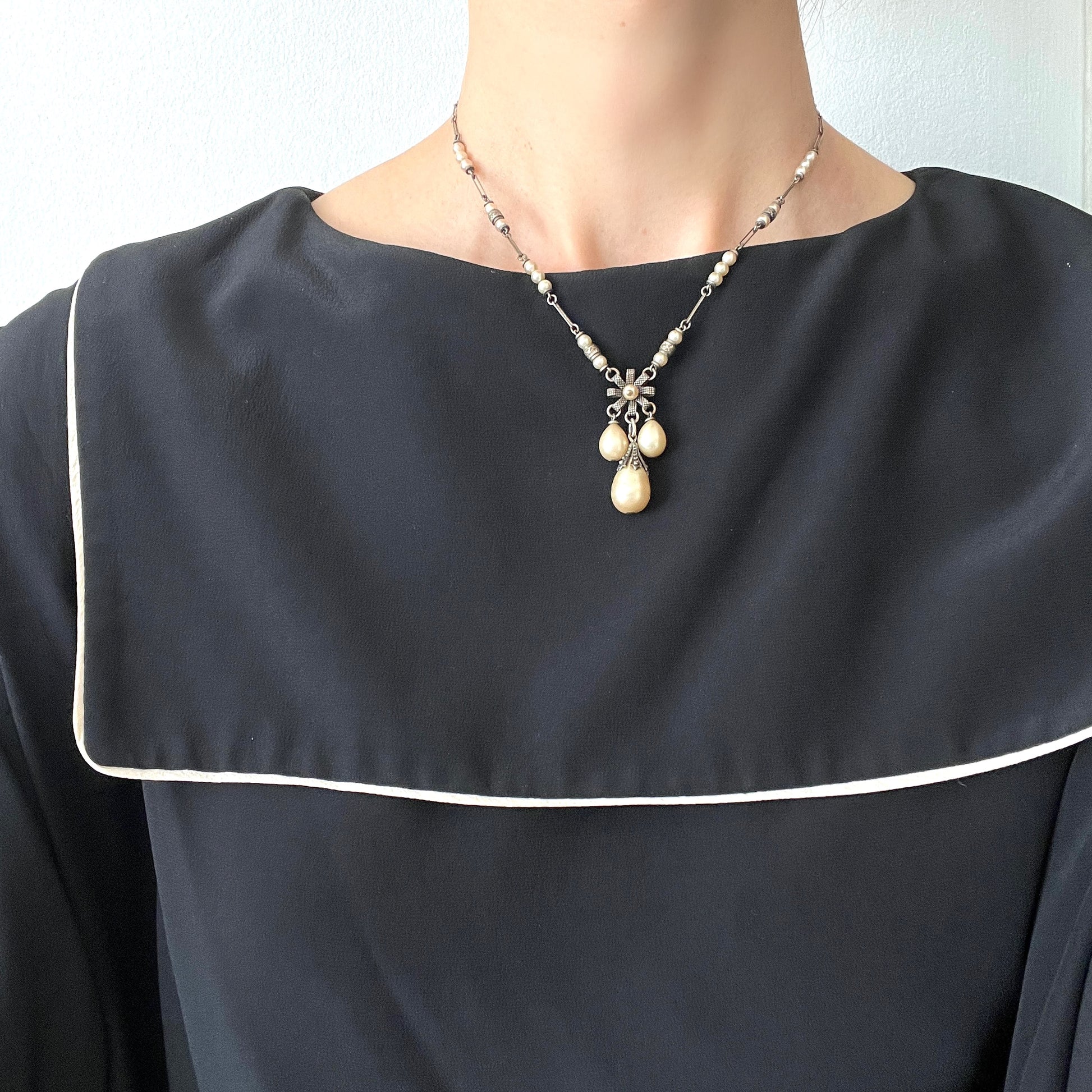 A necklace featuring metal flowers reminiscent of daisies, from which dangle chunky handmade teardrop glass pearls. デイジーのようなメタルのお花に、ゴロンとしたハンドメイドのティアドロップグラスパールがさがったネックレス。 