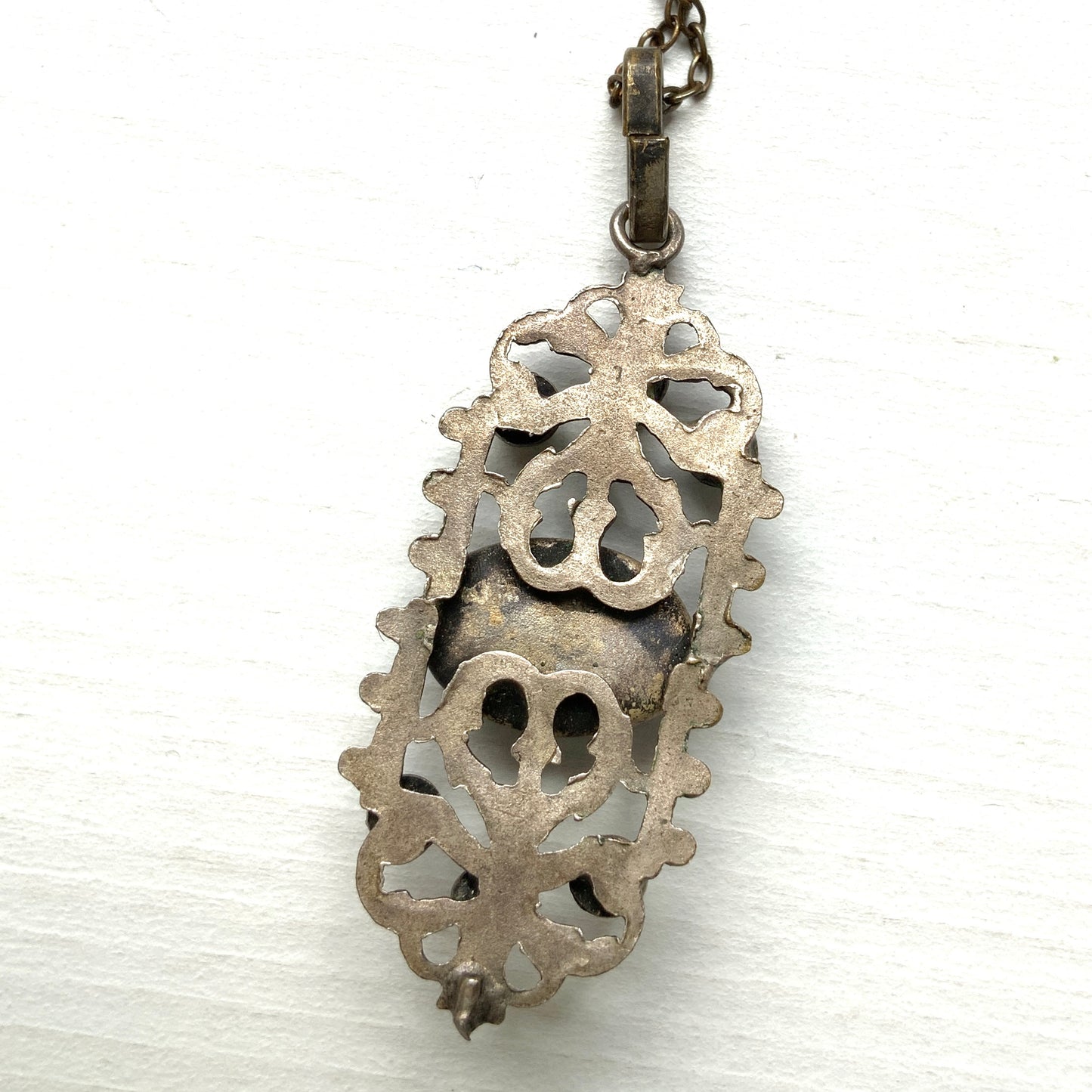 A delicate filigree pendant necklace adorned with a lapis glass cabochon, colourful rhinestones, and seed glass pearls. 繊細なフィリグリーのプレートに、ラピスグラスのカボションとカラフルなラインストーン、シードグラスパールがあしらわれたペンダントネックレス。 