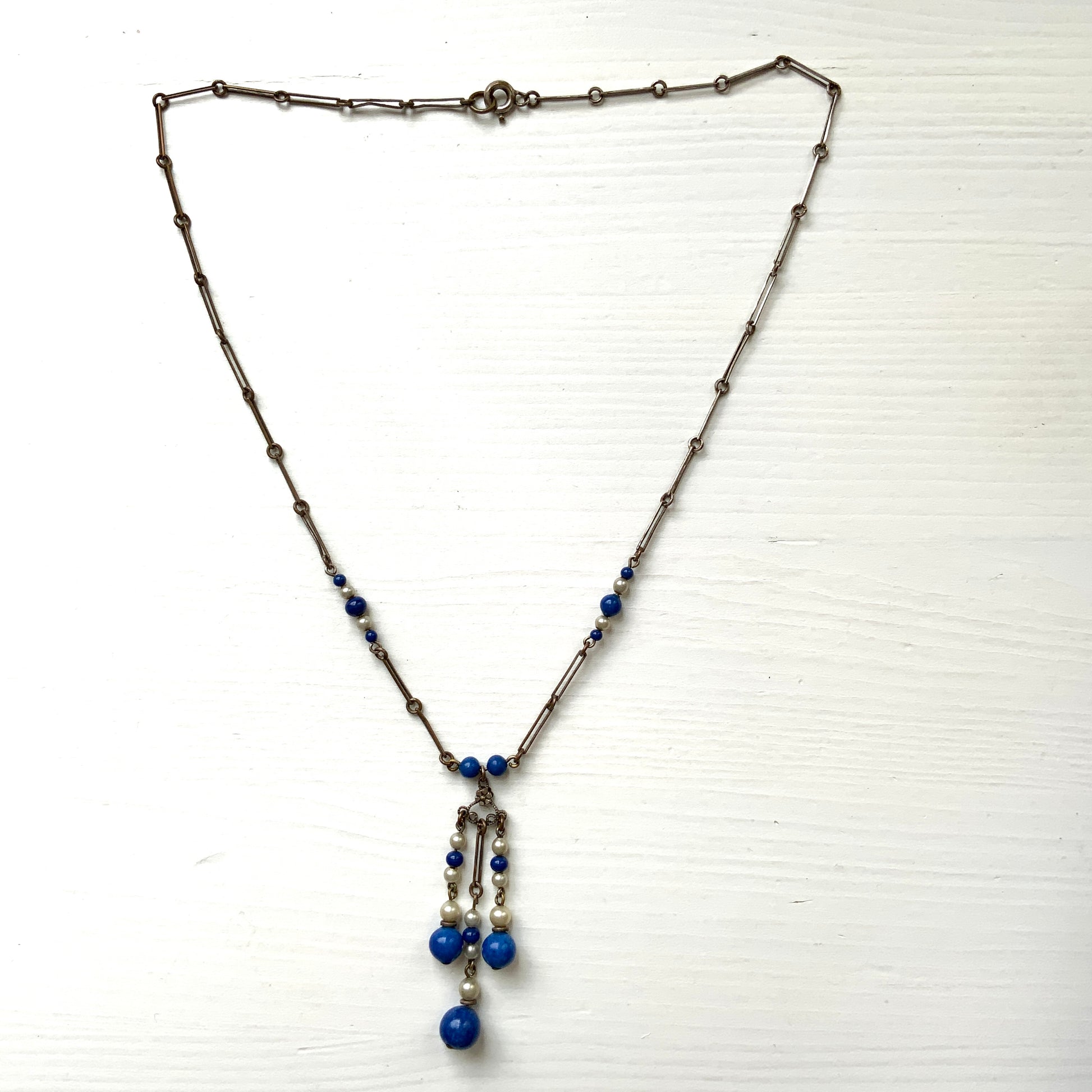 A fringe necklace featuring alternating small blue mottled glass beads and glass pearls.  小粒のブルー北京グラスとグラスパールが交互に連なってフリンジになったネックレス。