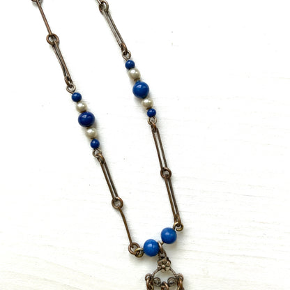 A fringe necklace featuring alternating small blue mottled glass beads and glass pearls.  小粒のブルー北京グラスとグラスパールが交互に連なってフリンジになったネックレス。