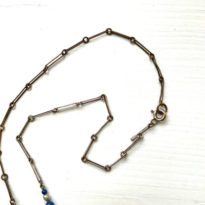 A fringe necklace featuring alternating small blue mottled glass beads and glass pearls.  小粒のブルー北京グラスとグラスパールが交互に連なってフリンジになったネックレス。