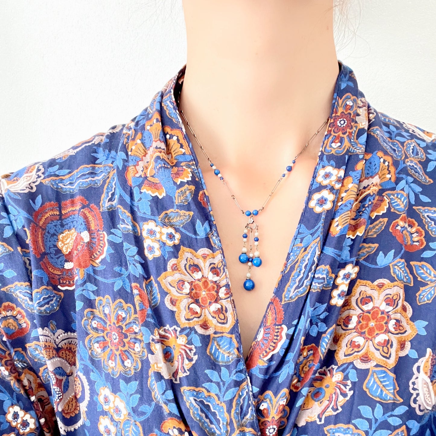 A fringe necklace featuring alternating small blue mottled glass beads and glass pearls.  小粒のブルー北京グラスとグラスパールが交互に連なってフリンジになったネックレス。