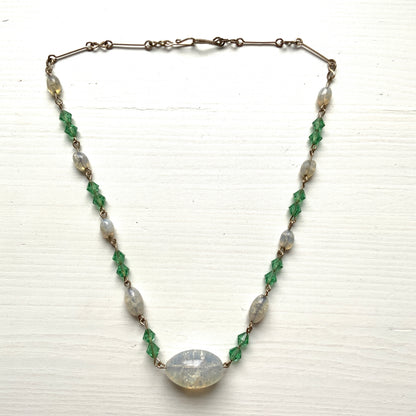 An opalescent crackle glass necklace accented with small green glass beads. オパルセントクラックルグラスに小さなグリーングラスを添えたネックレス。