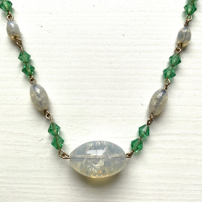 An opalescent crackle glass necklace accented with small green glass beads. オパルセントクラックルグラスに小さなグリーングラスを添えたネックレス。