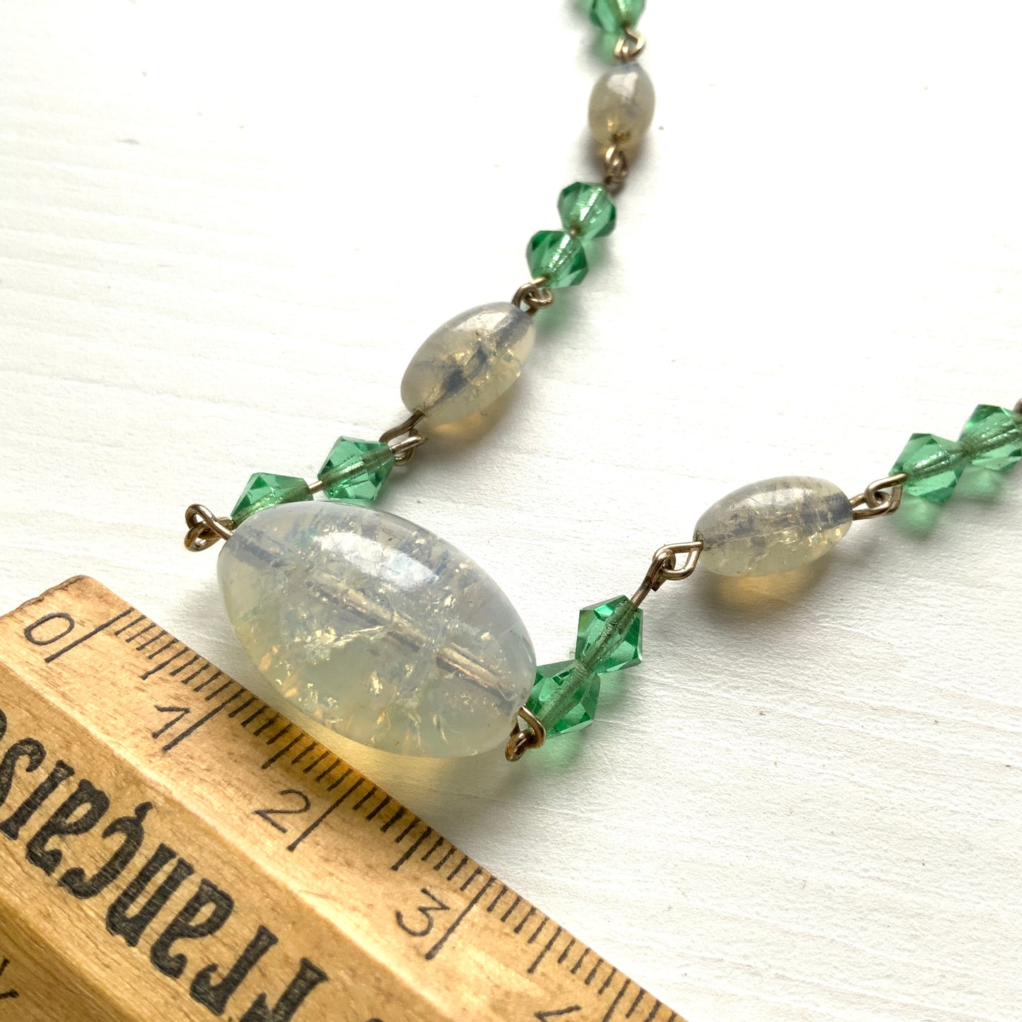 An opalescent crackle glass necklace accented with small green glass beads. オパルセントクラックルグラスに小さなグリーングラスを添えたネックレス。