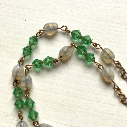 An opalescent crackle glass necklace accented with small green glass beads. オパルセントクラックルグラスに小さなグリーングラスを添えたネックレス。