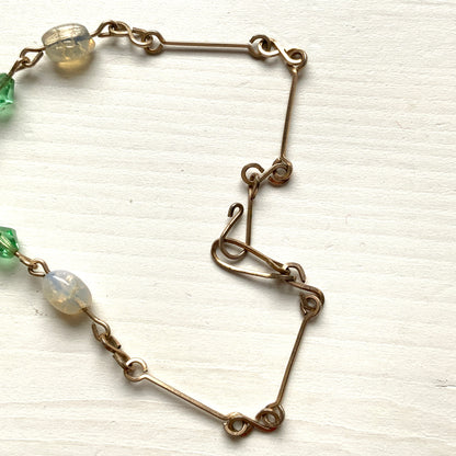 An opalescent crackle glass necklace accented with small green glass beads. オパルセントクラックルグラスに小さなグリーングラスを添えたネックレス。