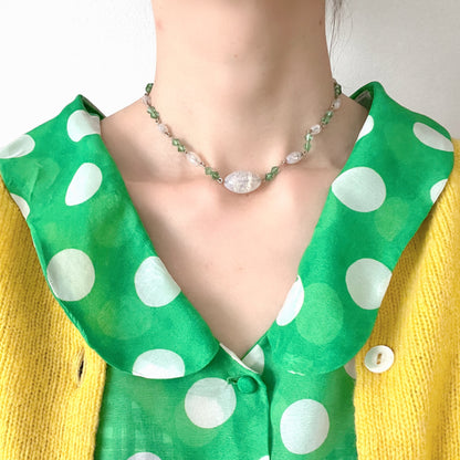 An opalescent crackle glass necklace accented with small green glass beads. オパルセントクラックルグラスに小さなグリーングラスを添えたネックレス。