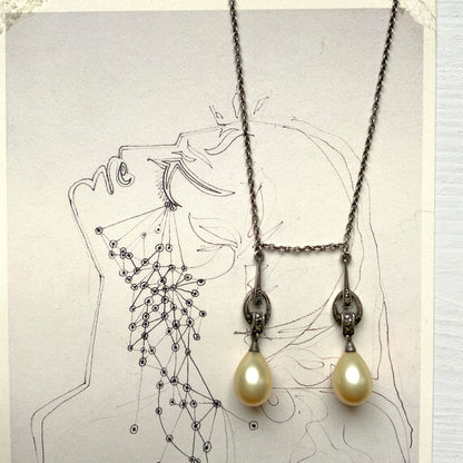 A silver necklace featuring delicate marcasite details and ivory teardrop pearls. マーカサイトの繊細なディテールとアイボリーのティアドロップパールが揺れるシルバーネックレス。